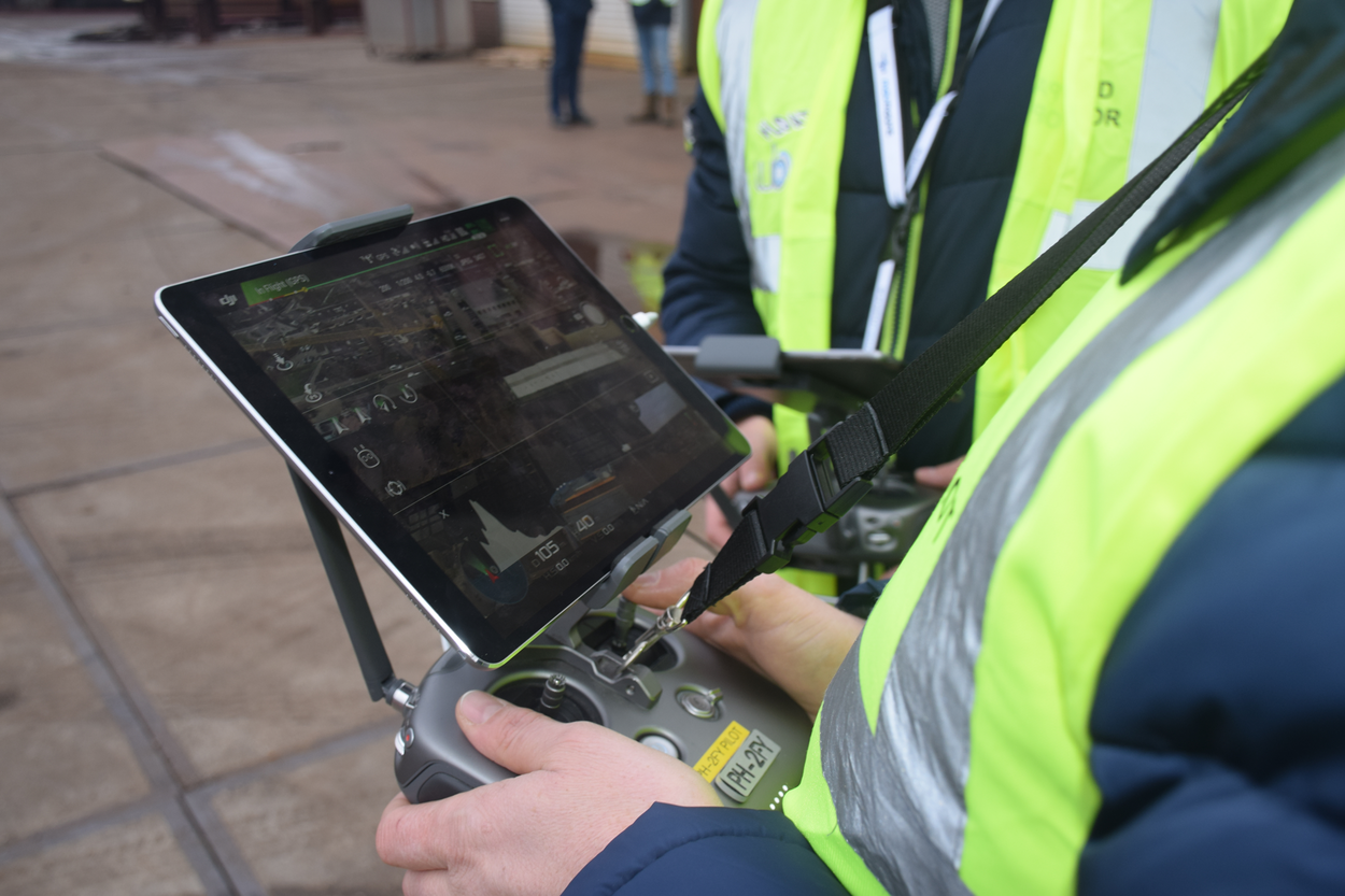 Een inspecteur houdt het bedienpaneel van een drone vast. Op het scherm zijn de dronebeelden zichtbaar.