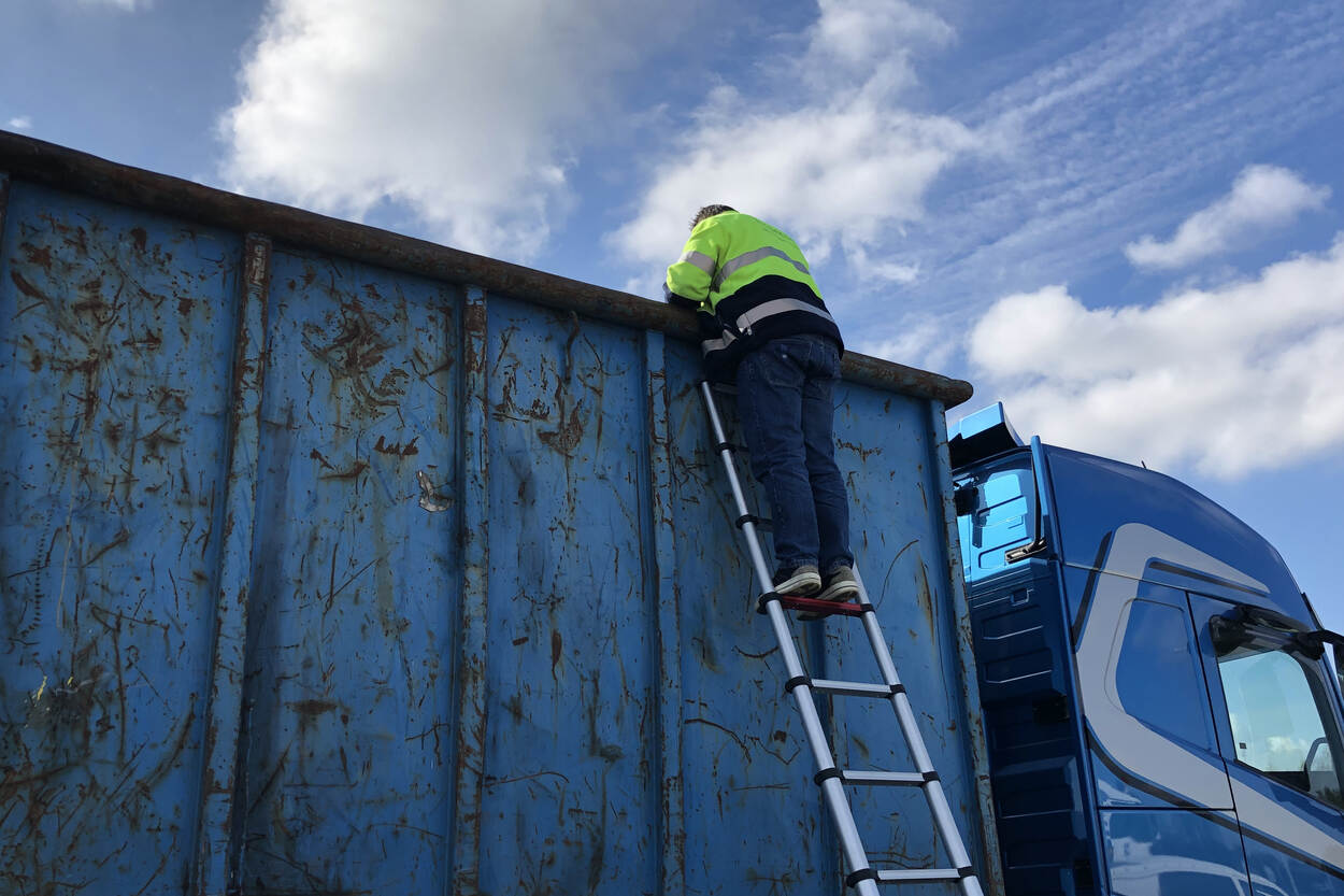 Een inspecteur staat op een lader en kijkt in een vrachtwagen.