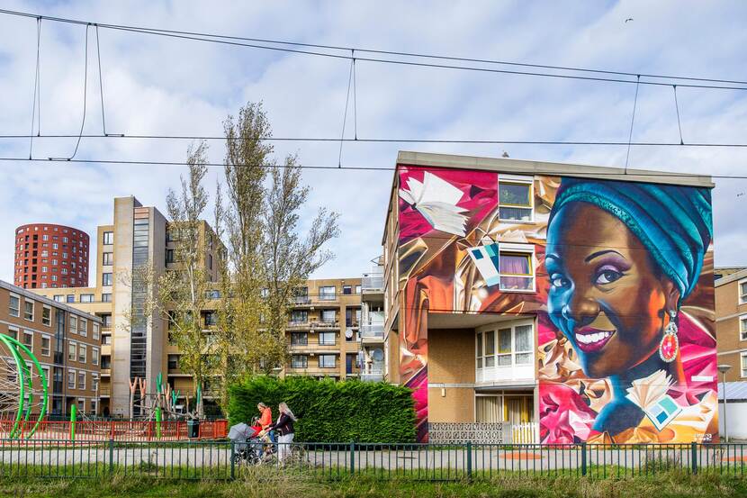 Meerdere appartementencomplexen staan naast elkaar. Op het voorste appartementencomplex is op de zijkant een muurschildering gemaakt van een vrouw.