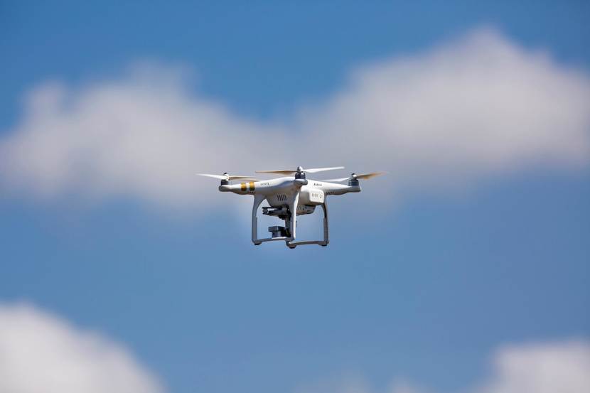 Een witgekleurde drone hangt in de lucht.