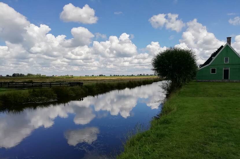 Landschap met brede sloten die een Hollandse wolkenlucht weerspiegelen. Locatie: Zaanse Schans.