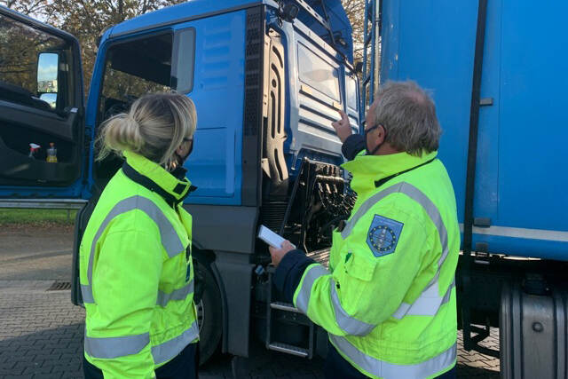 Inspecteurs voeren een internationale controle uit bij een vrachtwagen met een internationaal afvaltransport.