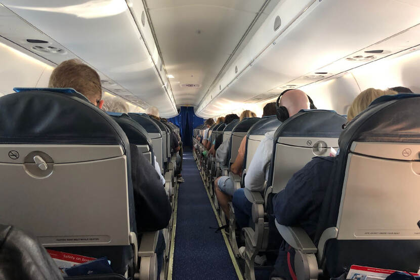 Vliegtuigpassagiers op stoelen in vliegtuig.
