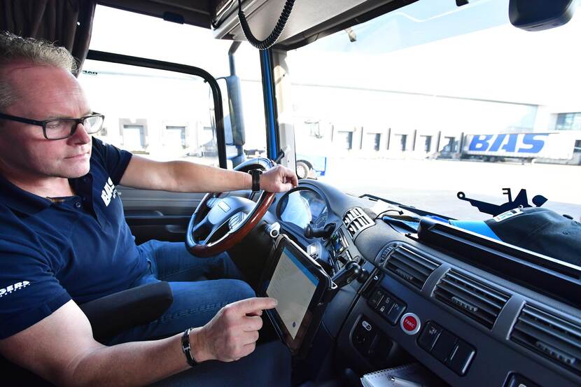 Vrachtwagenchauffeur in cabine van zijn vrachtwagen raadpleegt zijn boordcomputer.