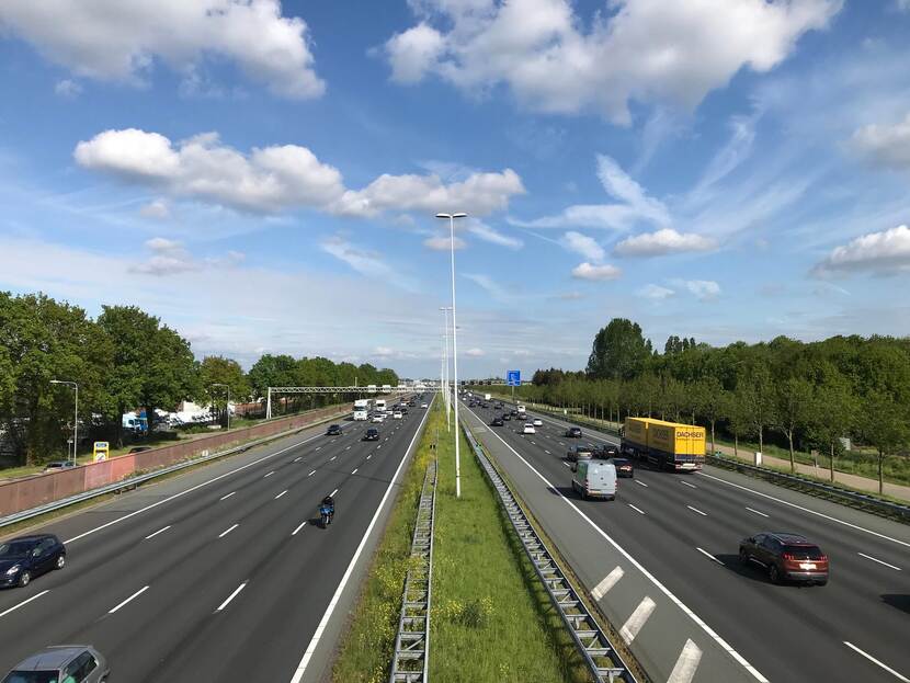 Uitzicht over de snelweg A12 vanaf een loopbrug. Auto's en vrachtwagens rijden voorbij.
