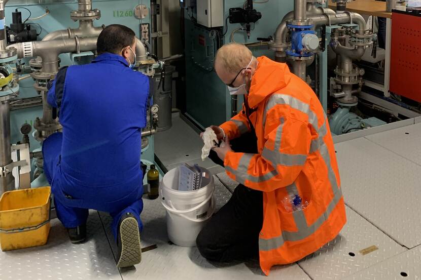 Inspecteurs nemen afvalwater-monsters aan boord van een zeeschip.