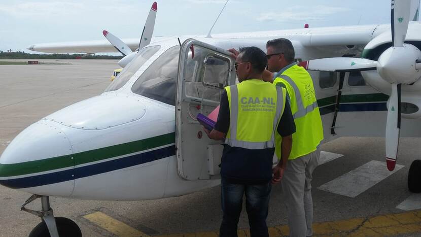 Inspecteurs bij de cockpit van een klein propellervliegtuig.