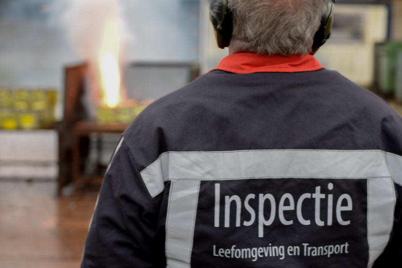 Inspecteur met gehoorbescherming controleert vuurwerk op veiligheid en kwaliteit.