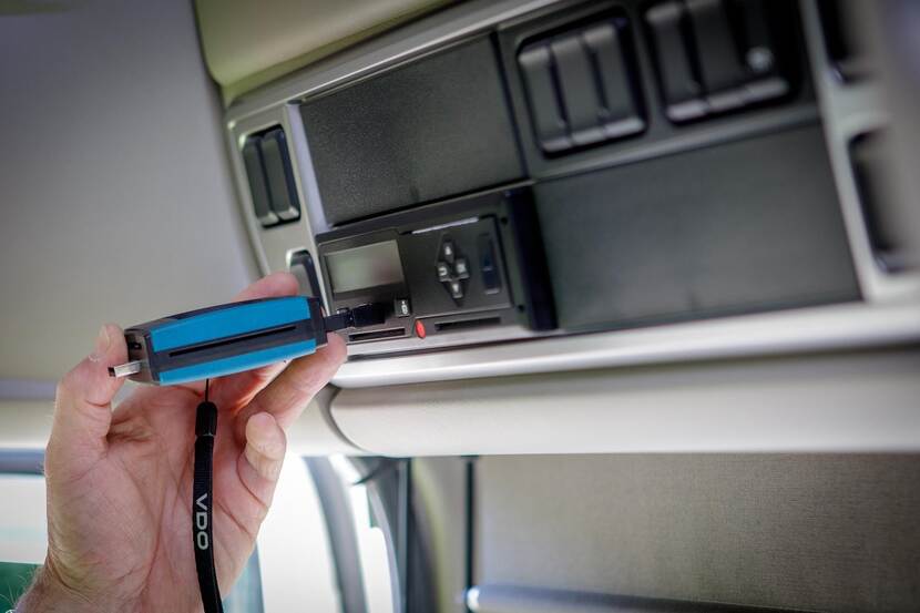 In de cabine van een vrachtwagen worden de rij- en rusttijden van een tachograaf digitaal uitgelezen.