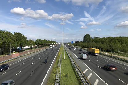 Auto's en vrachtwagens rijden over de snelweg de A12 bij Bunnik. Het is een zonnige zomerse dag.