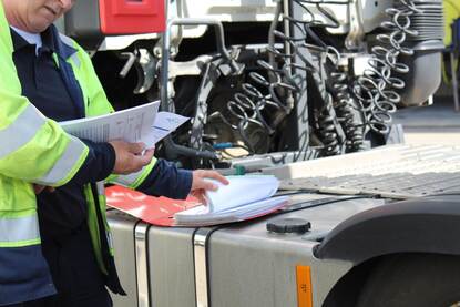 Een weginspecteur controleert de gegevens van een vrachtwagen.