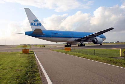Een groot KLM-passagiersvliegtuig taxiet over een groot vliegveld.