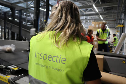 Een inspecteur controleert postpakketten bij een postsorteerbedrijf.