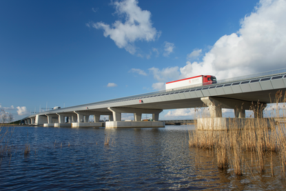 Een vrachtwagen rijdt over een brug over een rivier.