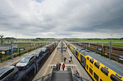 Een goederentrein en een passagierstrein passeren elkaar op een station.