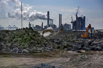 Op een afstand ligt een industriegebied. De schoorstenen roken.