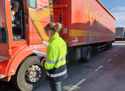Een inspecteur staat naast een vrachtwagen en controleert de papieren.