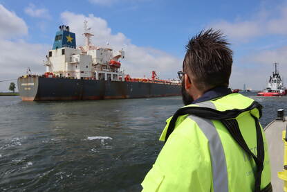 Een inspecteur kijkt naar een zeeschip  dat voorbijvaart bij Terneuzen.