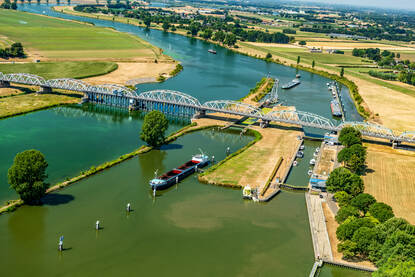 Een binnenvaartschip vaart over een rivier.
