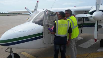 Inspecteurs bij de cockpit van een klein propellervliegtuig.