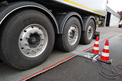 Ter controle van het van de lading rijdt een vrachtwagen op weegmatten.